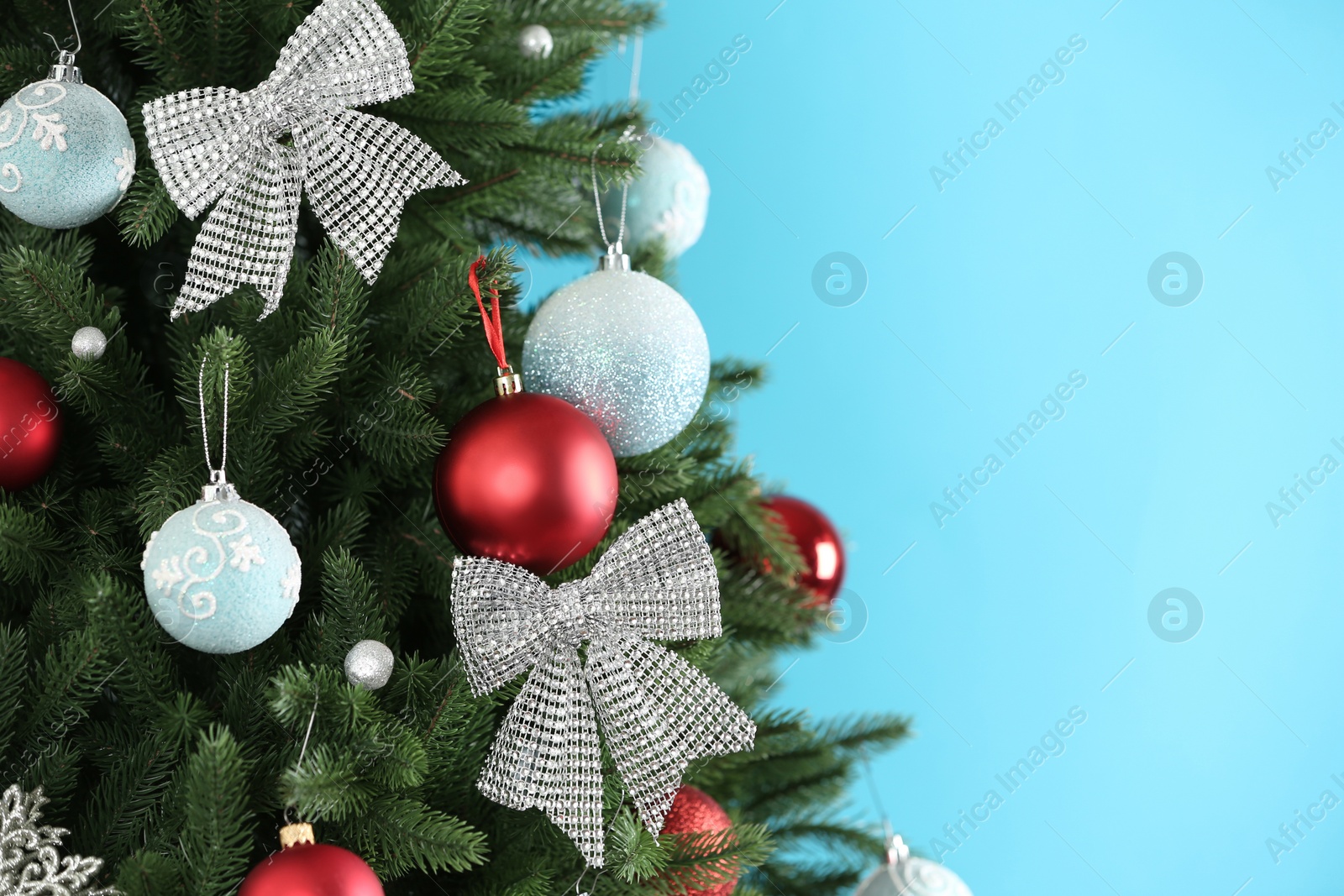 Photo of Beautiful Christmas tree with decor against light blue background. Space for text