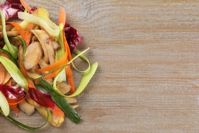 Photo of Peels of fresh vegetables on wooden table, top view. Space for text