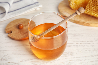 Photo of Glass jar of honey on white wooden table