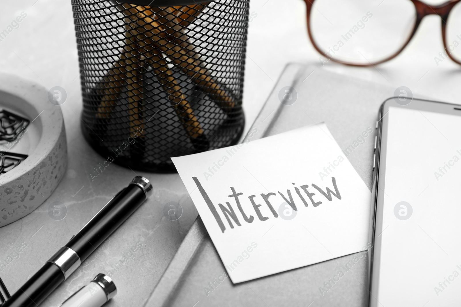 Photo of Reminder note about job interview and stationery on table, closeup