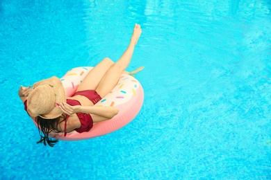 Photo of Beautiful young woman on inflatable ring in swimming pool