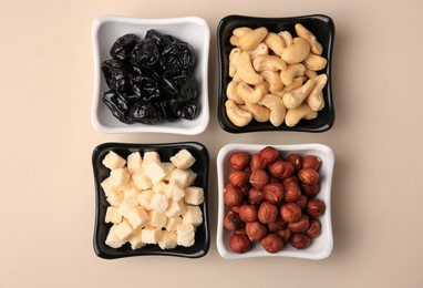 Photo of Bowls with dried fruits and nuts on beige background, flat lay