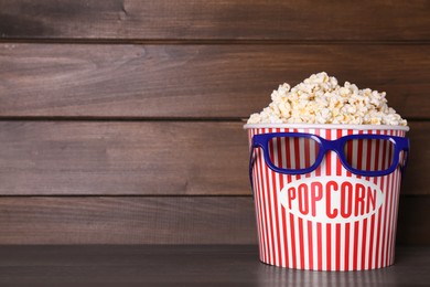 Delicious popcorn and 3D glasses on wooden table. Space for text