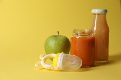 Photo of Healthy baby food, apple, juice and nibbler on yellow background, space for text