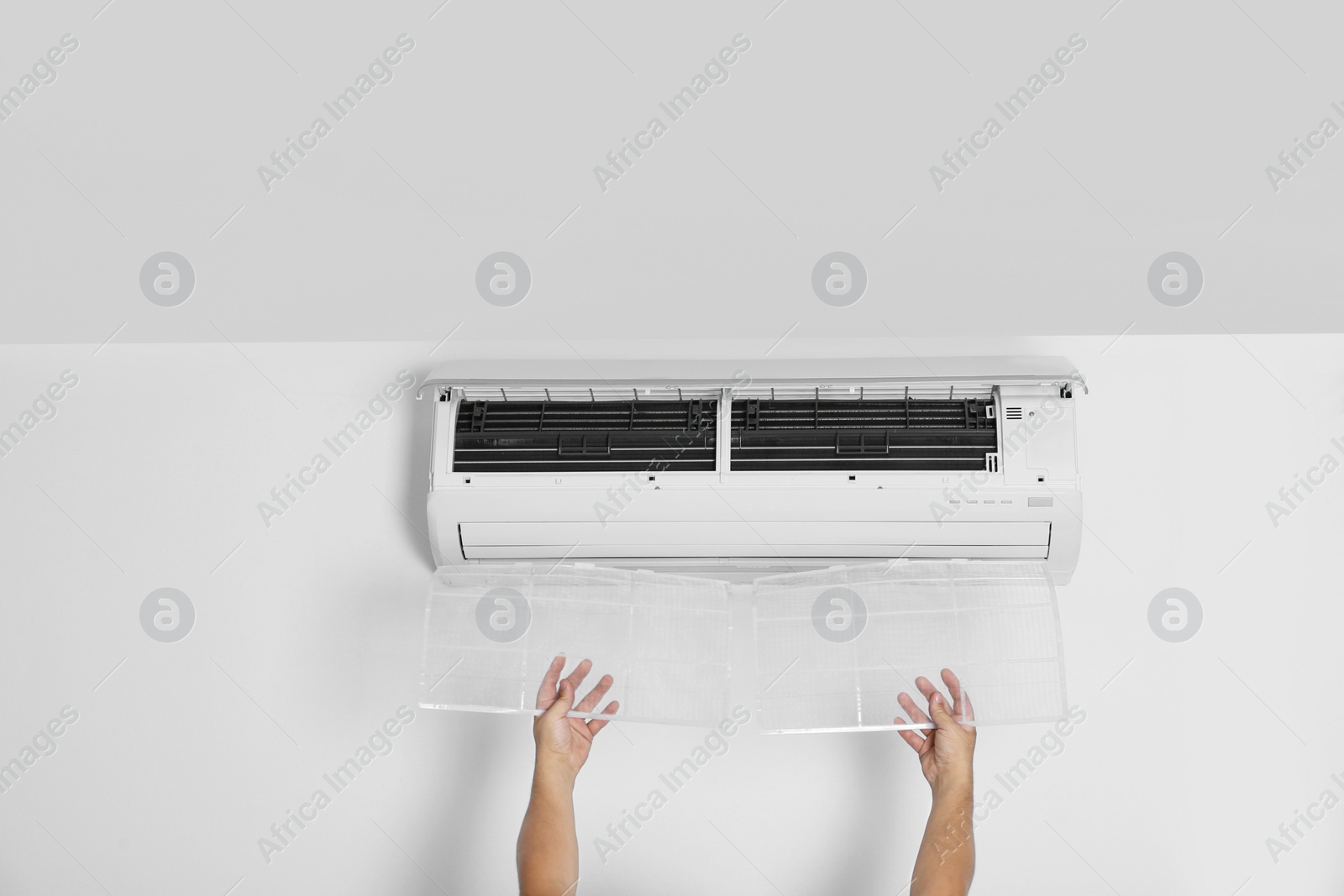 Photo of Man installing modern air conditioner indoors, closeup