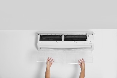 Photo of Man installing modern air conditioner indoors, closeup