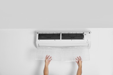 Man installing modern air conditioner indoors, closeup