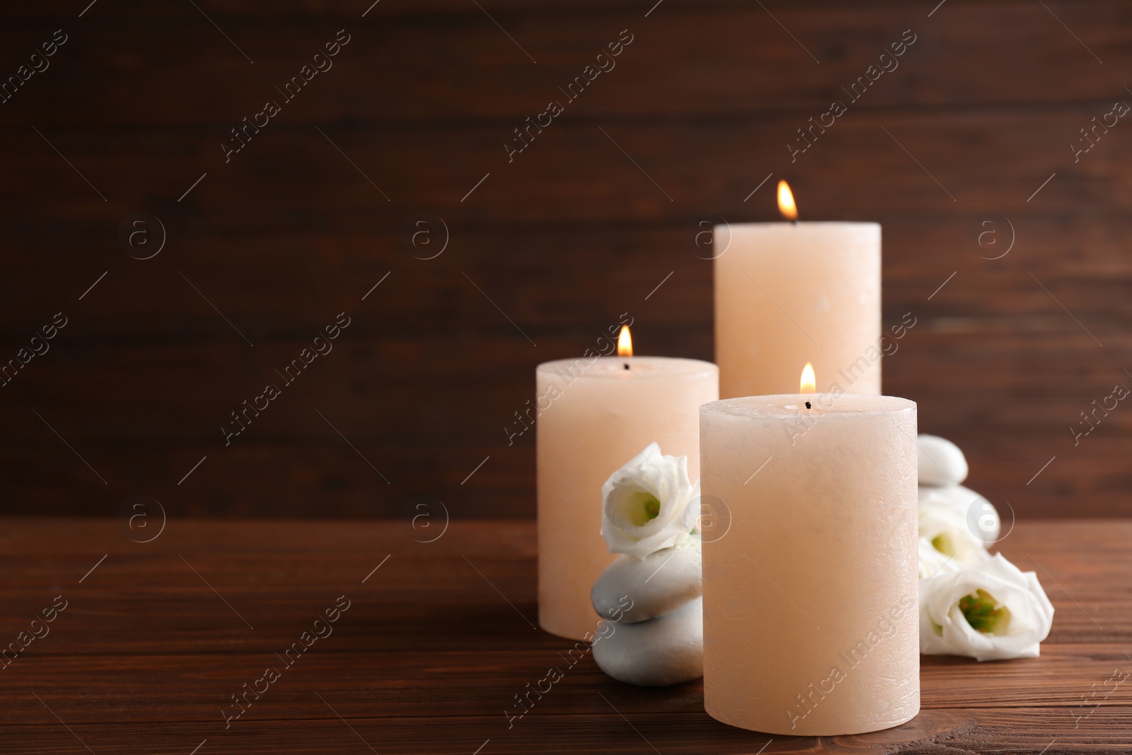 Photo of Composition of burning candles, spa stones and flowers on table. Space for text