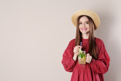 Photo of Beautiful young woman with Mason jar of natural detox lemonade on beige background. Space for text