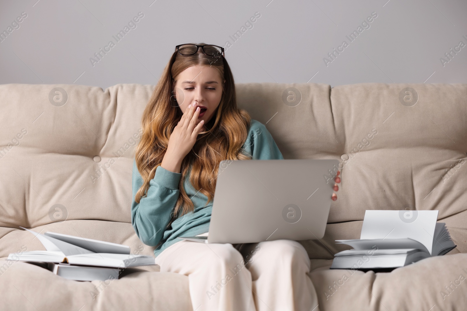 Photo of Young tired woman studying on couch indoors