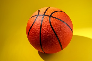 Photo of One new basketball ball on yellow background, closeup