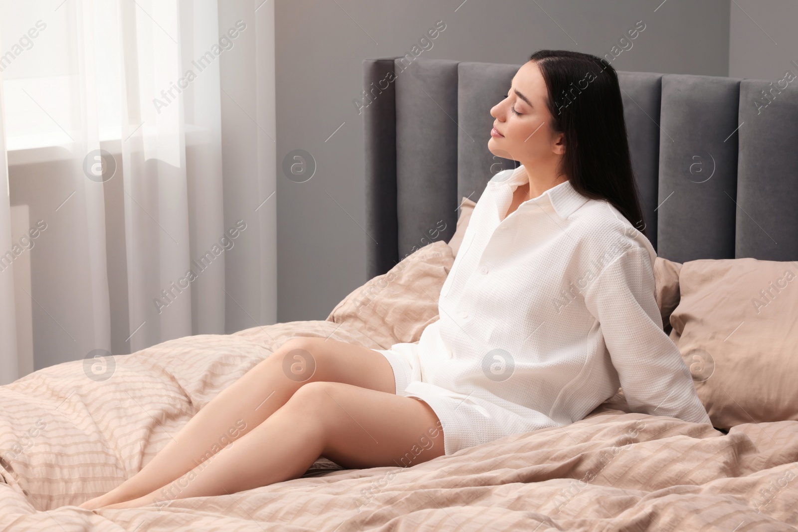 Photo of Beautiful woman sitting on bed at home. Lazy morning