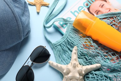 String bag and different beach accessories on light blue background