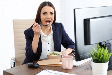 Photo of Office employee having salad for lunch at workplace. Food delivery