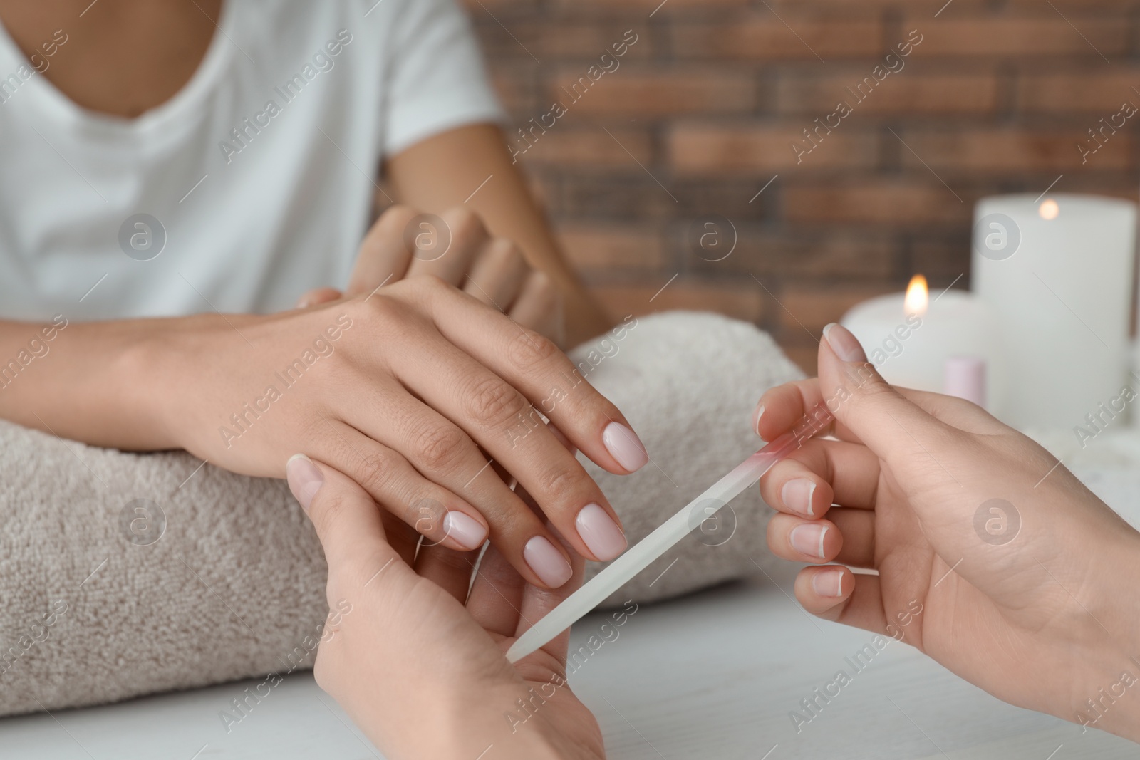 Photo of Manicurist filing client's nails at table, closeup. Spa treatment