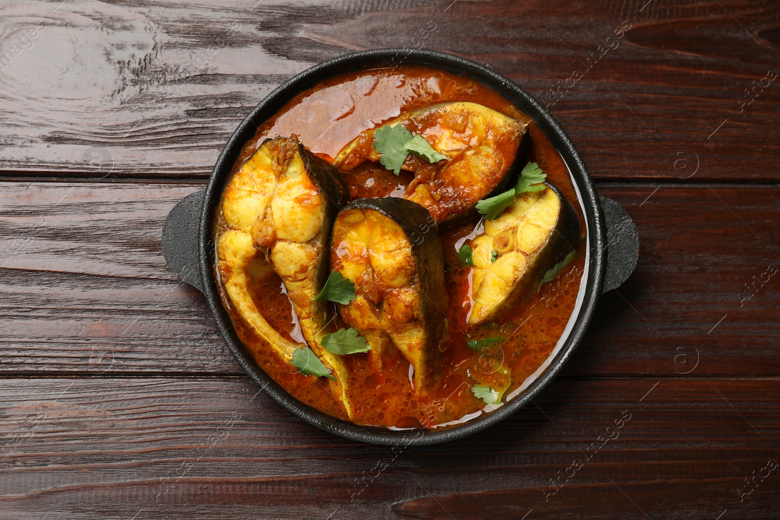 Photo of Tasty fish curry on wooden table, top view. Indian cuisine