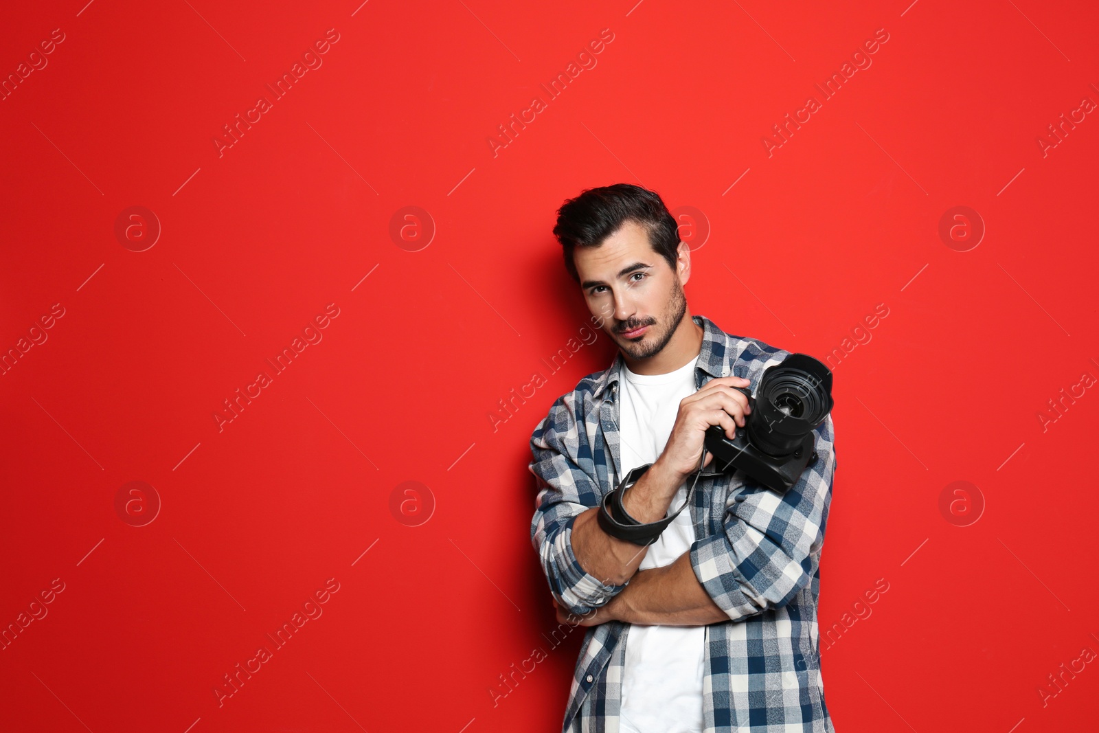 Photo of Young photographer with professional camera on red background. Space for text