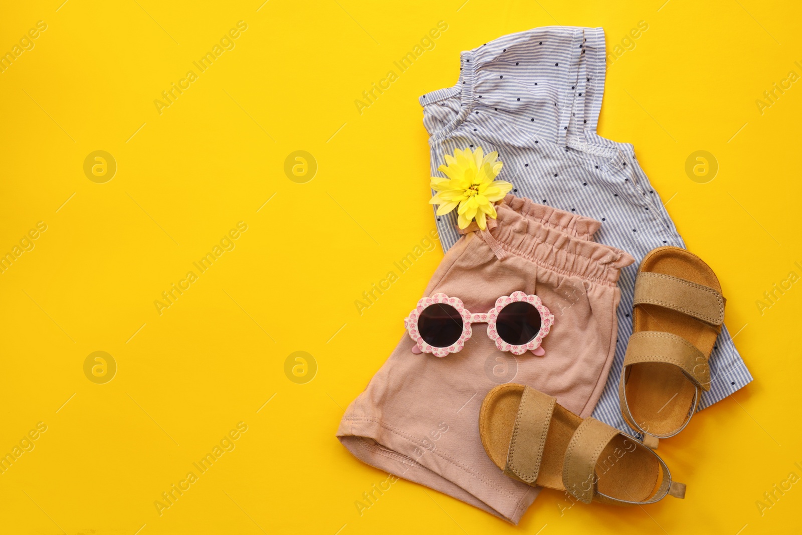 Photo of Stylish child clothes, shoes and sunglasses on yellow background, flat lay. Space for text