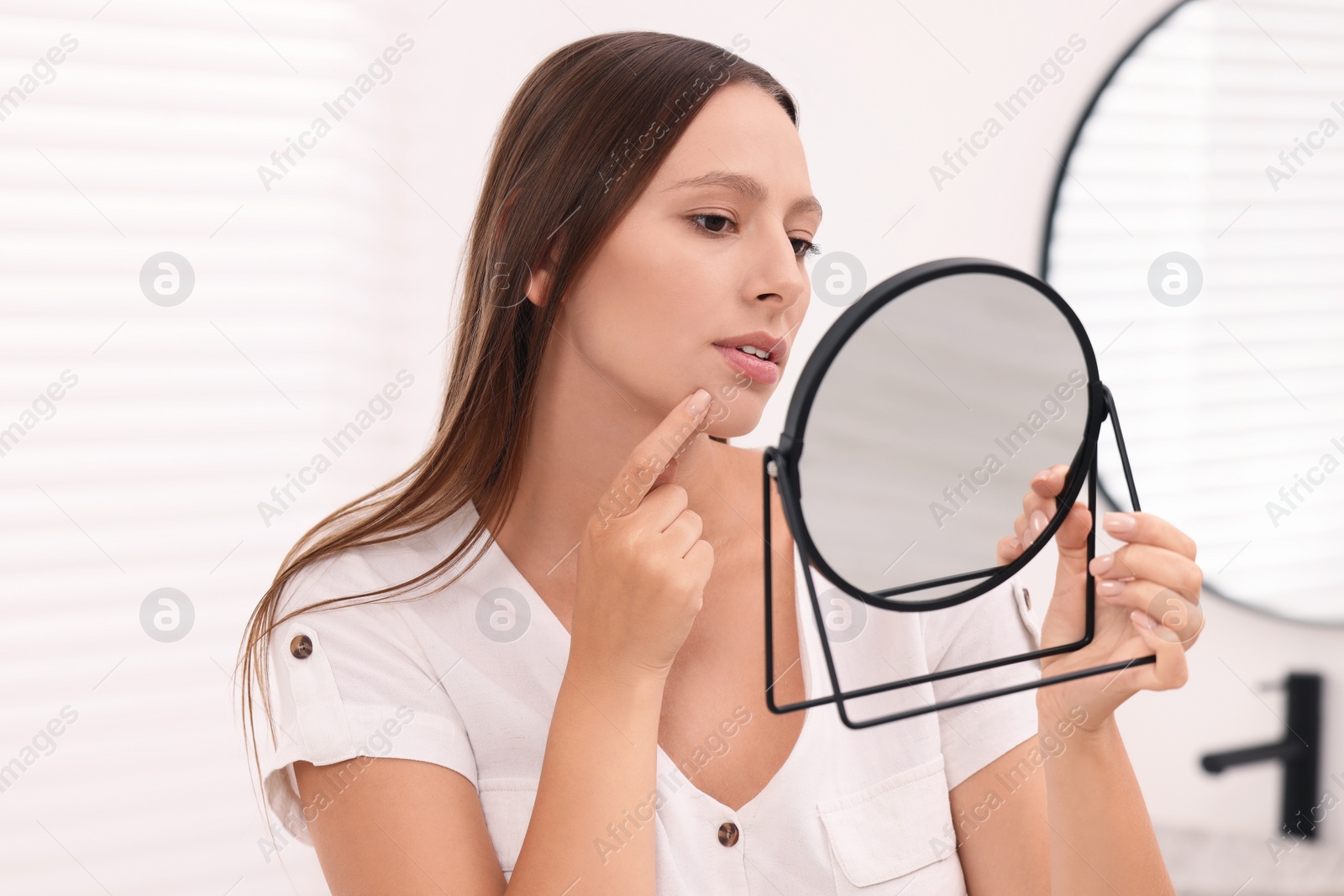 Photo of Woman with skin problem looking at mirror indoors