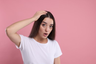 Emotional woman with healthy dark hair on pink background, space for text. Dandruff problem