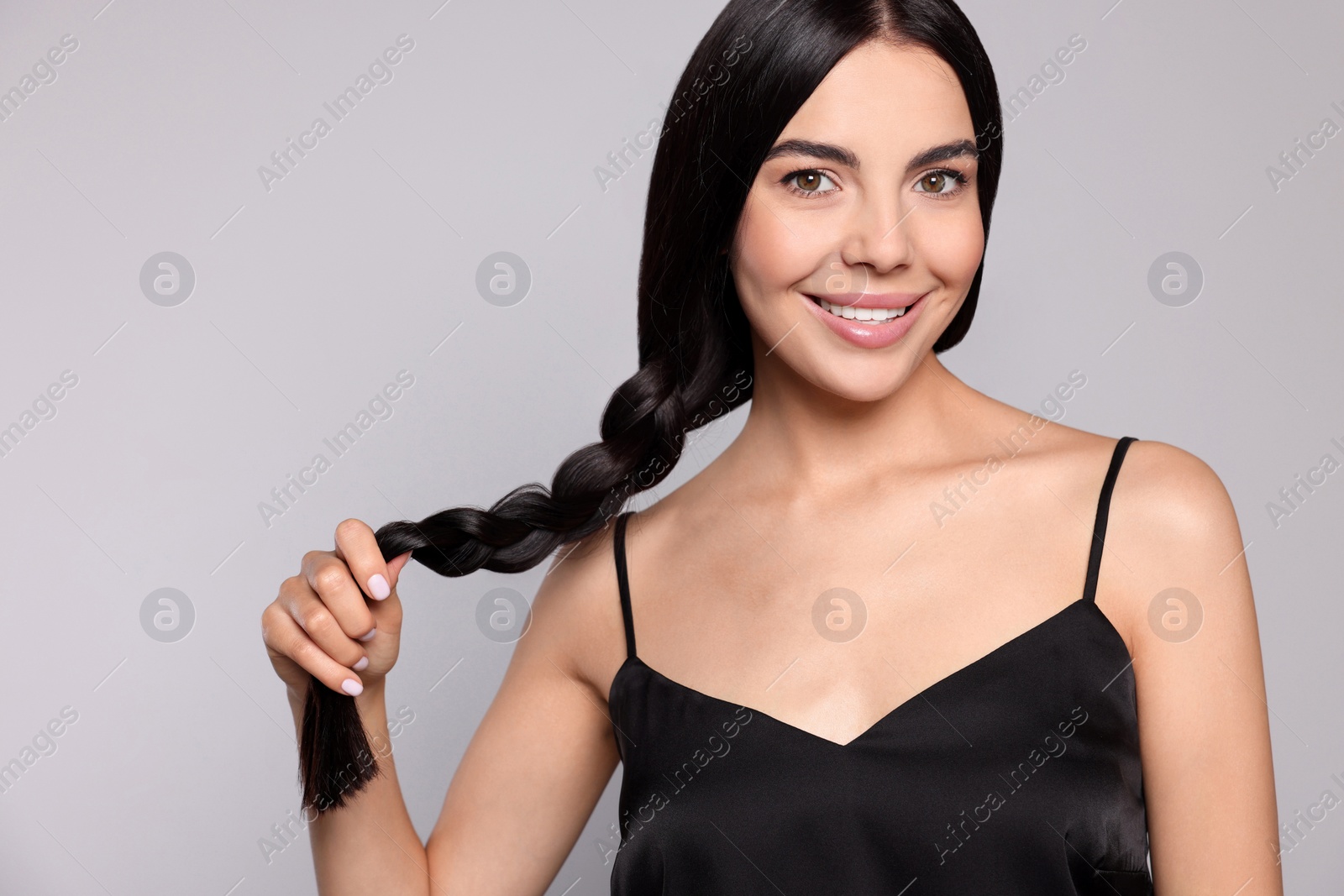 Photo of Portrait of beautiful young woman with healthy strong hair on light grey background, space for text