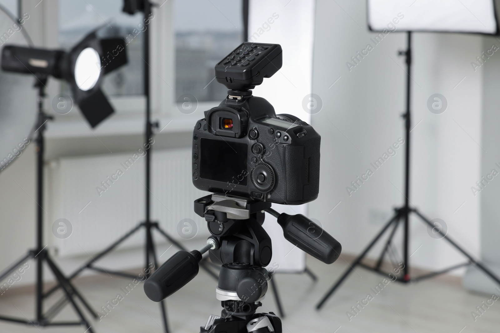 Photo of Camera on tripod and professional lighting equipment in modern photo studio