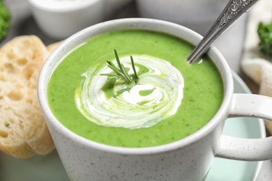 Tasty kale soup with cream and rosemary on table , closeup