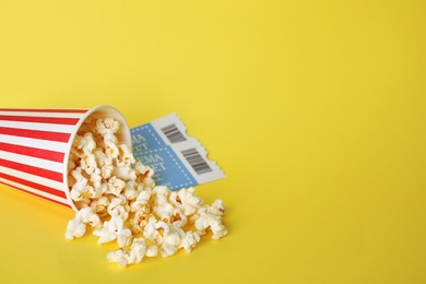 Photo of Delicious popcorn and tickets on yellow background. Space for text