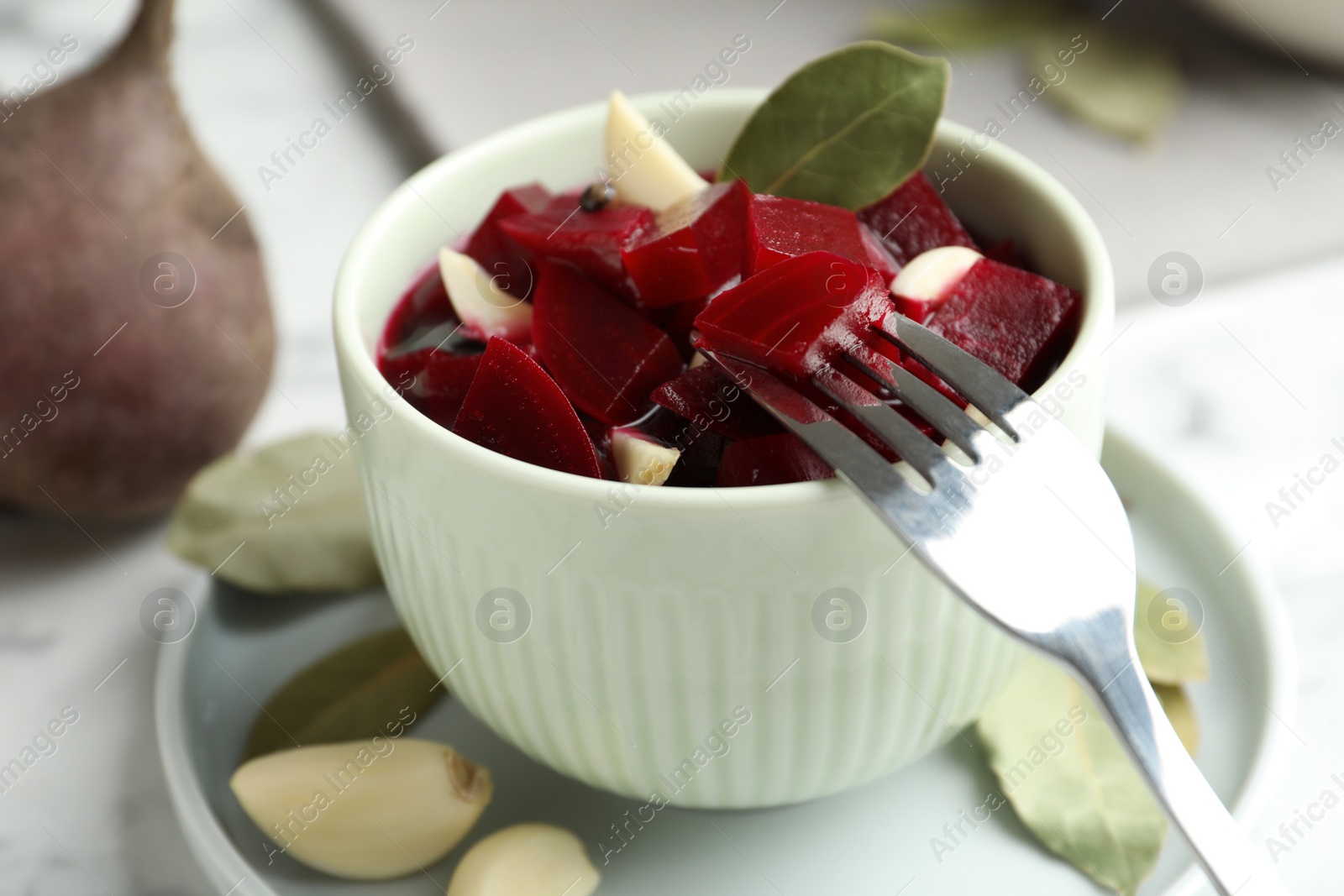 Photo of Pickled beets with garlic in bowl on table, closeup