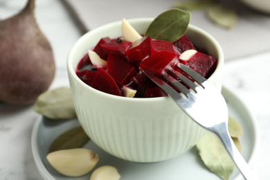 Pickled beets with garlic in bowl on table, closeup