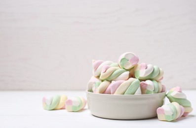 Photo of Bowl with colorful marshmallows on white table. Space for text