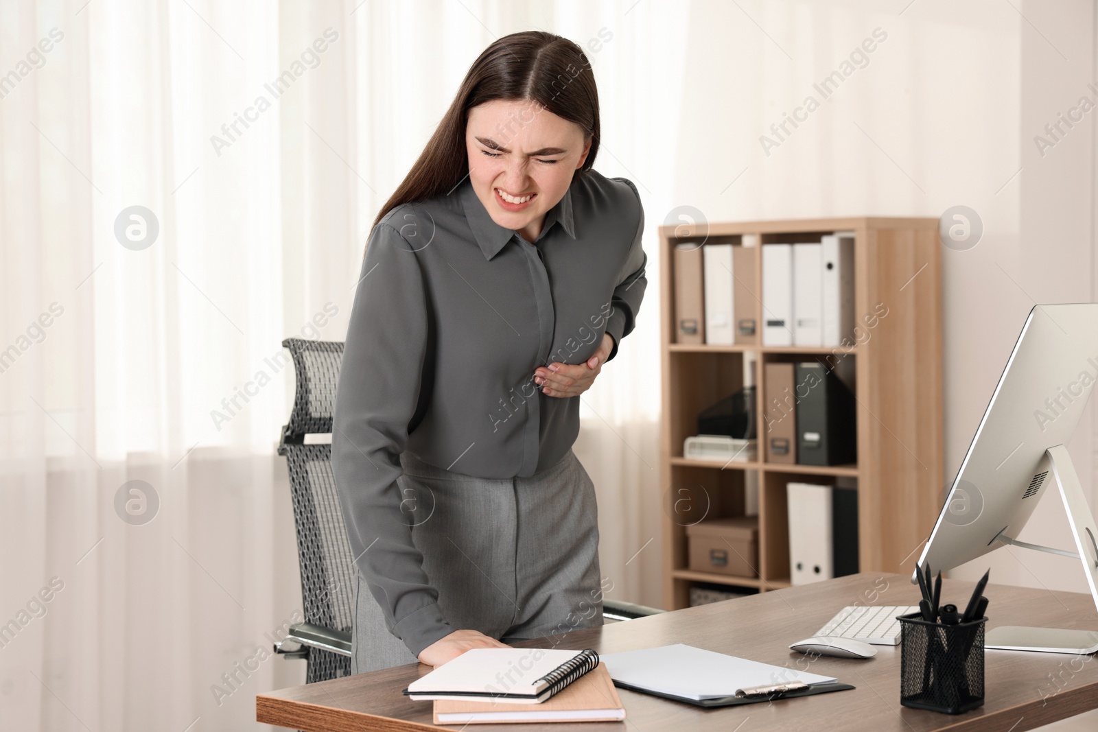 Photo of Woman having heart attack near table in office