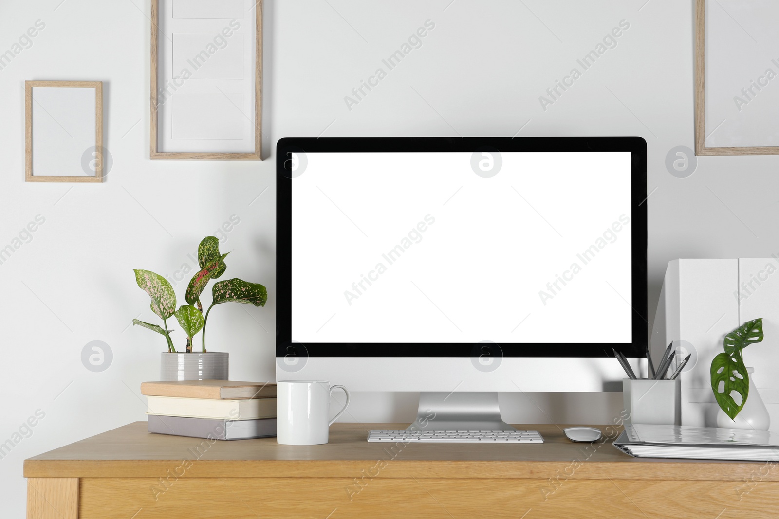 Photo of Home workplace. Computer, stationery and houseplants on wooden desk