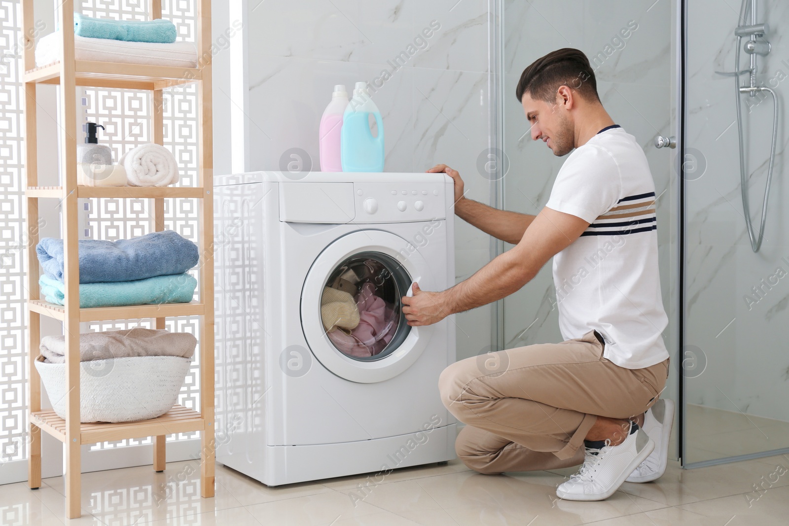 Photo of Man near washing machine in bathroom. Laundry day