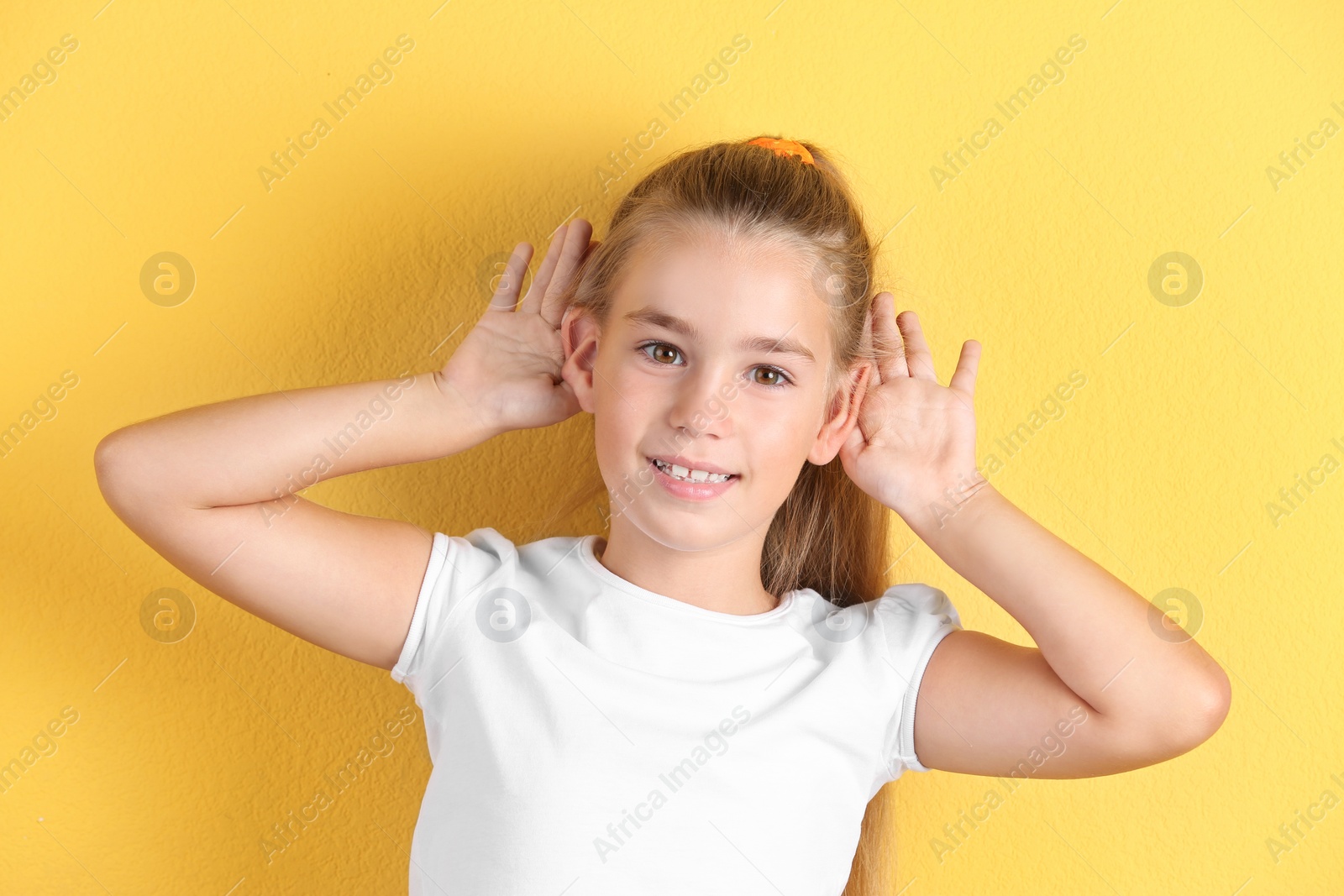 Photo of Cute little girl with hearing problem on color background