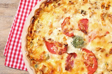Tasty quiche with tomatoes and cheese on wooden table, top view