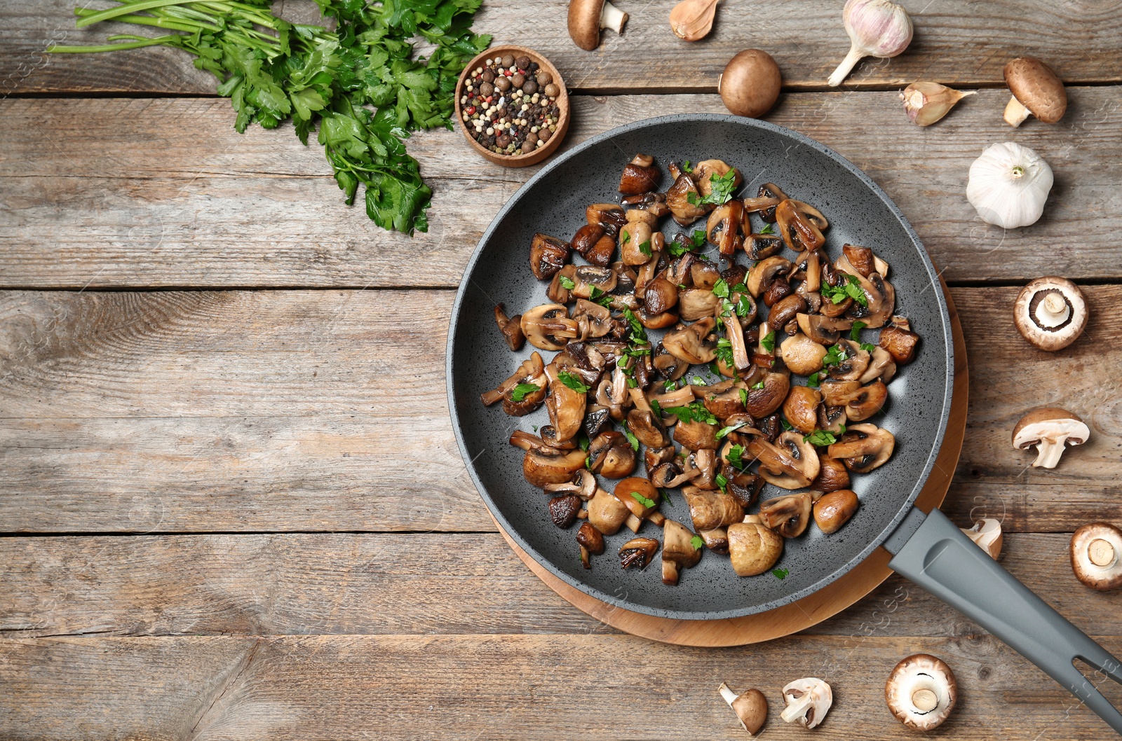 Photo of Frying pan of mushrooms on wooden background, flat lay with space for text