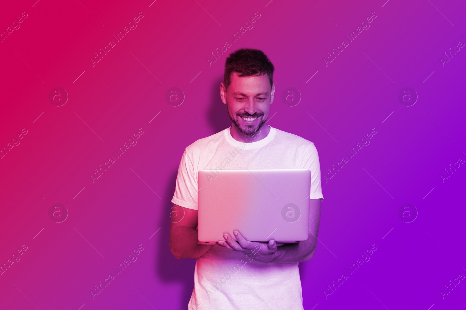 Image of Handsome man with laptop in neon lights