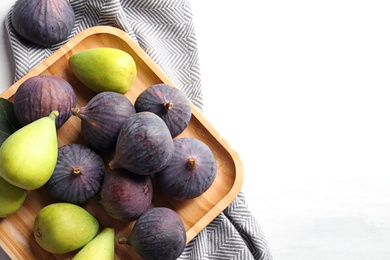 Photo of Plate with assorted ripe figs on light background, top view. Space for text