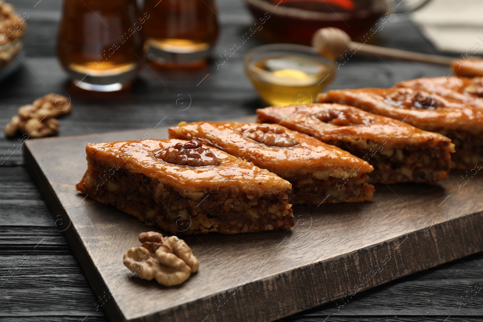 Photo of Delicious sweet baklava with walnuts on black wooden table, closeup