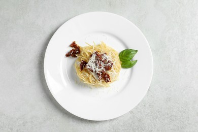 Photo of Tasty spaghetti with sun-dried tomatoes and parmesan cheese on white table, top view. Exquisite presentation of pasta dish