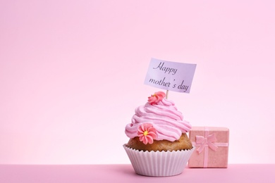 Photo of Tasty cupcake and gift box for Mother's Day on color background