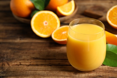 Photo of Glass of orange juice and fresh fruits on wooden table