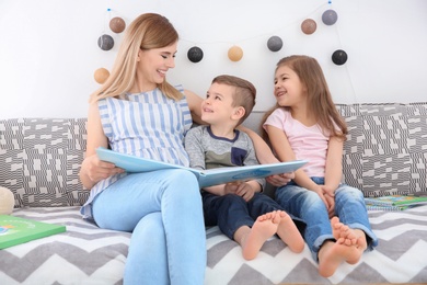 Nanny reading book to little children at home