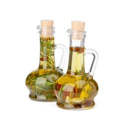 Photo of Glass jugs of cooking oils with spices and herbs on white background