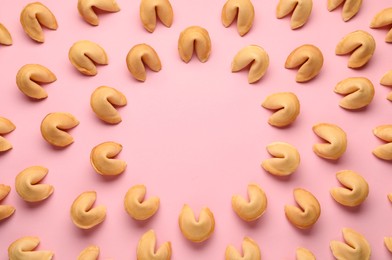 Frame of tasty fortune cookies with predictions on pink background, flat lay. Space for text
