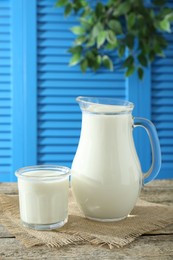 Jug and glass of fresh milk on wooden table