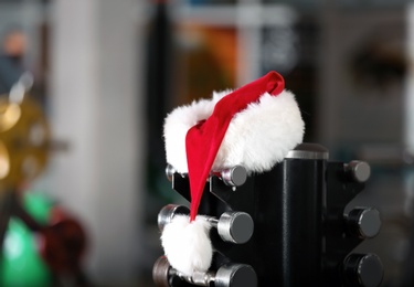 Photo of Santa Claus hat on stand with dumbbells in gym