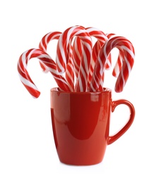 Red cup with sweet Christmas candy canes isolated on white