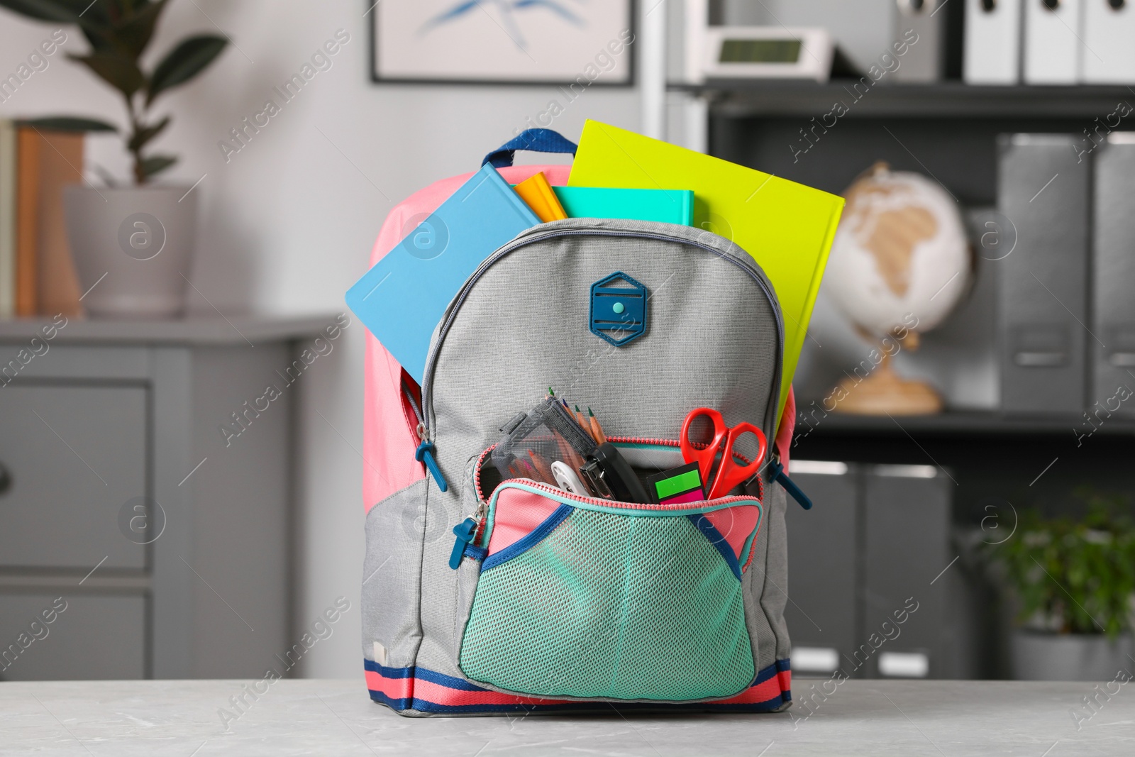 Photo of Children's backpack with different school stationery on table indoors